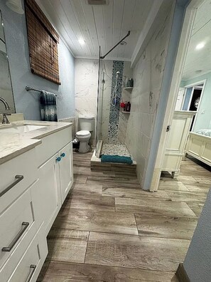 Un baño pequeño con ducha, inodoro y lavamanos.