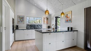 Une cuisine moderne avec des meubles blancs, un plan de travail en marbre et des luminaires suspendus.