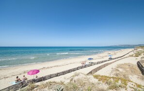 En strand med klar himmel, en sandstrand och en stenmur som löper parallellt med stranden.