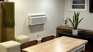 Een kleine keuken met een houten tafel en stoelen, een ingebouwde airconditioner en een potplant.