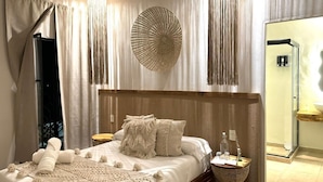 A bedroom with a large bed, a bedside table, a mirror, and a view of a bathroom. - HOTEL ALEIA. Centro (Taxco)