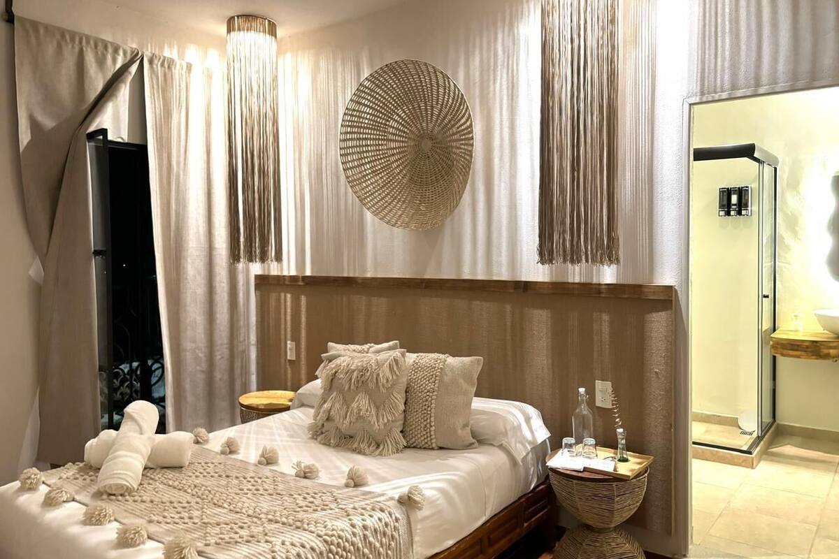 A bedroom with a large bed, a bedside table, a mirror, and a view of a bathroom.