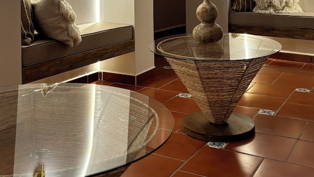 A spa room with arched alcoves, a glass table, and a woven chair. - HOTEL ALEIA. Centro (Taxco)