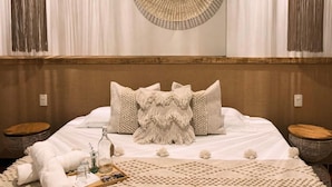 A bedroom with a large bed, two bedside tables, a woven wall hanging, and a textured rug. - HOTEL ALEIA. Centro (Taxco)