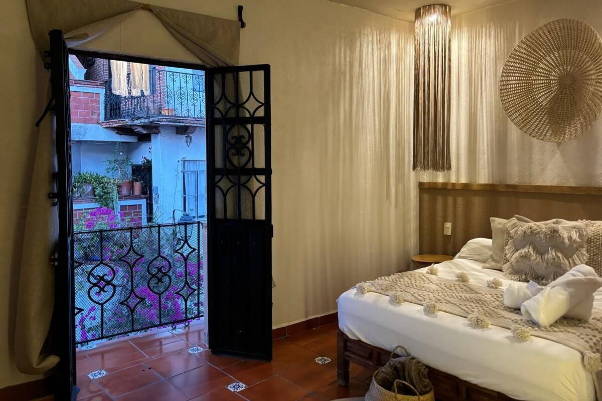 A bedroom with a bed, curtains, and a decorative wall piece.