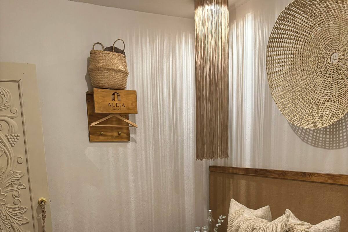 A neatly made bed with a textured blanket and pillows, a wooden headboard, and a wall-mounted woven basket.