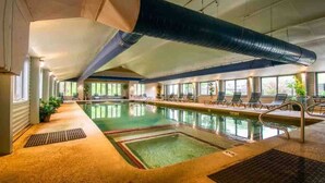 Ein Innenpool mit klarem Wasser, umgeben von Liegestühlen und einer großen Überstromdecke.