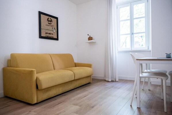 Ein gelbes Sofa, ein weißer Tisch und ein Fenster mit Vorhängen.