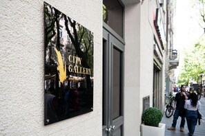 Schild für die CITY GALLERY APARTMENTS mit Blick auf die Straße und die Gebäude.