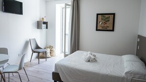 A hotel room with a bed, a desk, a chair, and a television. - City Gallery Apartments (Trieste)