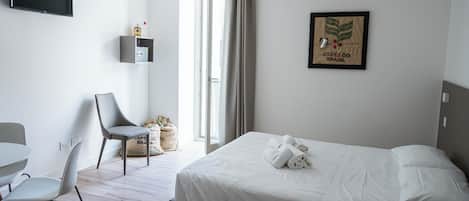 A hotel room with a bed, a desk, a chair, and a television.
