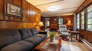 Una sala de estar acogedora con sofá, sillón y una mesita con una planta.