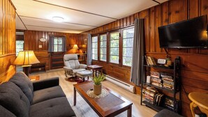 Una sala de estar acogedora con un sofá, sillón, mesita de centro y estantería.