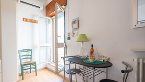 Et lille spiseområde med et bord, stole, en lampe og en stol ved et vindue.