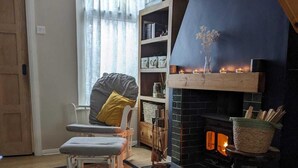 Una sala de estar acogedora con chimenea, un sillón cómodo, una estantería y una alfombra.
