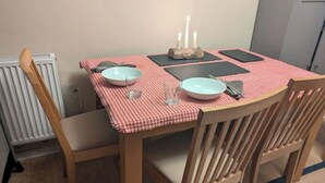 Una mesa de comedor con mantel a cuadros, dos cuencos, cubiertos y velas.