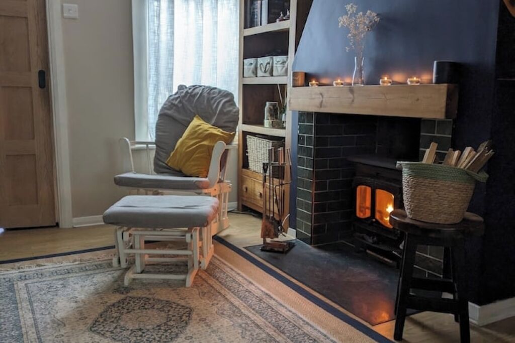 A cozy living room with a fireplace, a comfortable chair, and a bookshelf.