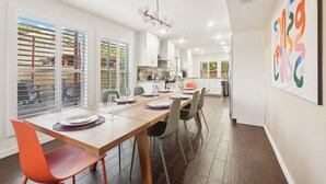 A modern kitchen with white cabinets, a wooden countertop, and a hanging light fixture. - Cobo Escape | Heated Pool | MiniGolf | Game Room (Scottsdale)