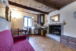 Una habitación acogedora con chimenea, vigas de madera, un sofá rojo y un comedor.