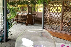 A patio area with a table and chairs, a glass enclosure, and a green plant. - MyExclusiveItaly - Entire Hilltop Villa with Private Pool (Palazzuolo Sul Senio)