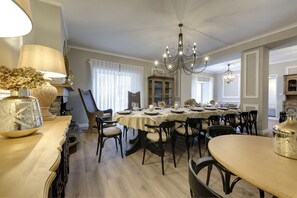 Une salle à manger agrémentée d’un lustre, une table à manger dressée pour six personnes et un buffet aux portes vitrées.