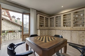 Un comedor con un tablero de ajedrez, una pared de piedra y un balcón con vistas a edificios.