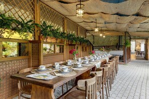 A long wooden dining table set with plates, cups, and a vase of flowers.