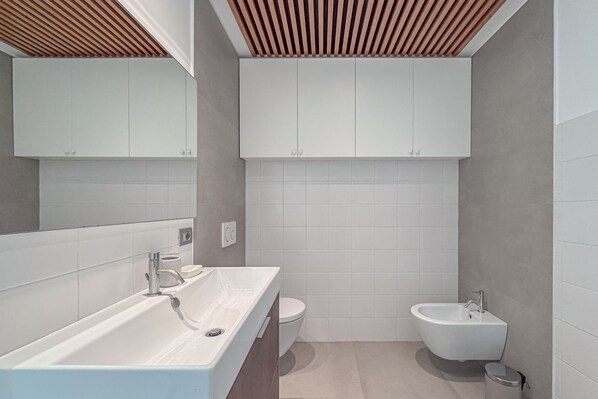 Un baño moderno con una bañera grande, un inodoro y un bidé.