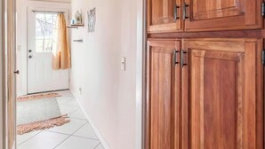 Un pasillo con un armario de madera, suelo de baldosas y techo con vigas a la vista.