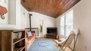 Un salón acogedor con techo de madera, un sofá, un televisor y una silla.