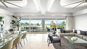 A modern living room with a glass dining table, comfortable seating, and a view of the beach. - Mayan Island Horizonte 303 Calakmul (Nuevo Nayarit)
