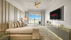 A modern hotel room with a large bed, a TV mounted on the wall, and a balcony with a view of palm trees. - Mayan Island Horizonte 303 Calakmul (Nuevo Nayarit)