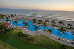 Un resort con varias piscinas, una playa y vista al océano.