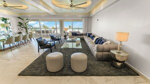 A spacious living room with a large sofa, a coffee table, and a dining area with chairs and a glass table. - Mayan Island Horizonte 303 Calakmul (Nuevo Nayarit)