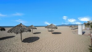 A beach with thatched umbrellas and a water fountain. - Mayan Island Horizonte 303 Calakmul (Nuevo Nayarit)