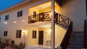 A two-story building with a balcony, a staircase, and outdoor seating. - Vacation apartment with pool  (Willemstad)