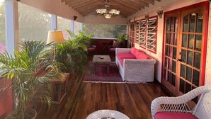 Una habitación acogedora con techo de madera, un candelabro, un sofá rojo y una silla de mimbre.