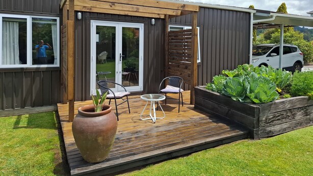A compact wooden house with a patio, a sliding glass door, and a car parked outside. - Nine on Cochrane - relax, unwind and explore Rotorua. (Rotorua)