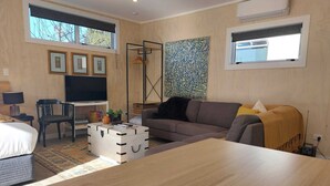 A modern living room with a sofa, a wooden coffee table, a TV, and a painting on the wall. - Nine on Cochrane - relax, unwind and explore Rotorua. (Rotorua)