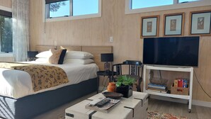 A modern bedroom with a large bed, bedside tables, a TV, and framed artwork on the wall. - Nine on Cochrane - relax, unwind and explore Rotorua. (Rotorua)
