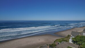 Uma praia com vista clara para o oceano, areal arenoso e edifícios residenciais ao primeiro plano.