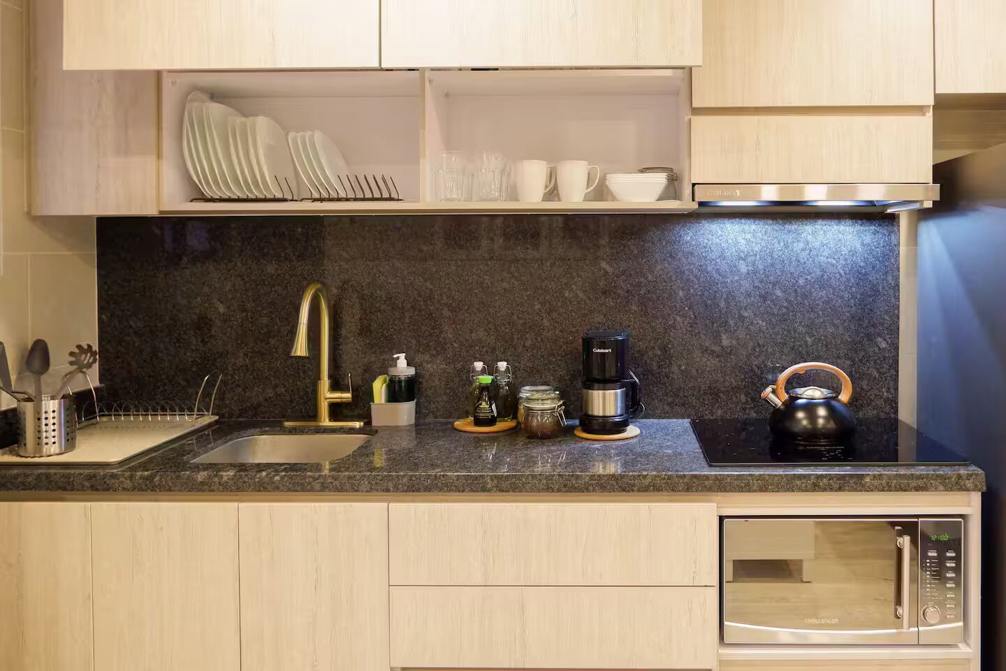 A modern kitchen with a granite countertop, stainless steel appliances, and wooden cabinets.