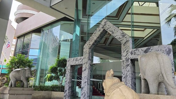 A modern building entrance with glass facades, a stone elephant sculpture, and a stone lion sculpture. - First Pacific Cirrus - Pattaya (Pattaya)