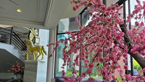 A modern interior with a large window, a golden horse statue, and a pink flowering tree. - First Pacific Cirrus - Pattaya (Pattaya)