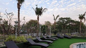 A poolside area with lounge chairs and artificial grass. - First Pacific Cirrus - Pattaya (Pattaya)