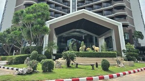 A high-rise building with a central entrance, multiple balconies, and surrounding greenery. - First Pacific Cirrus - Pattaya (Pattaya)