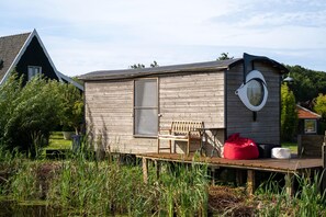 A small wooden cabin with a deck, a bench, and a red bean bag. - Apartment in Netherlands Near the Coast (t Zand)