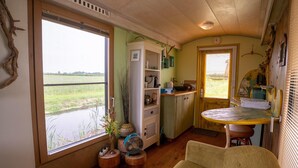 Un acogedor interior de cabaña con un ventanal grande, muebles de madera y un pequeño comedor.