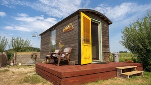 Una cabaña de madera con puerta amarilla, una terraza con sillas y un letrero que dice "Hammelster".