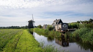 Un canal con un molino y una casa con ventana circular.